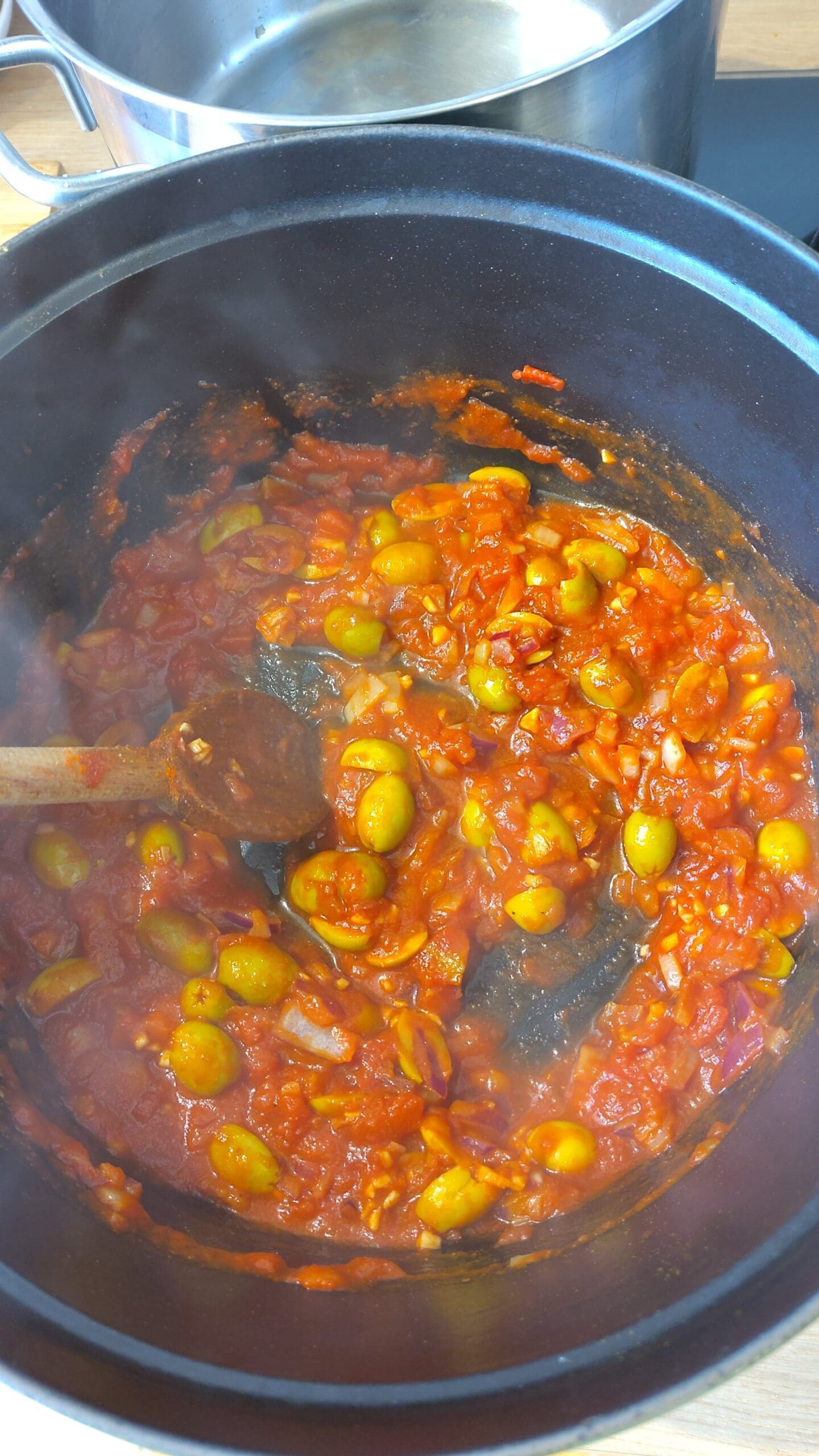 Les olives et la tomate cuisent dans la cocotte en fonte.